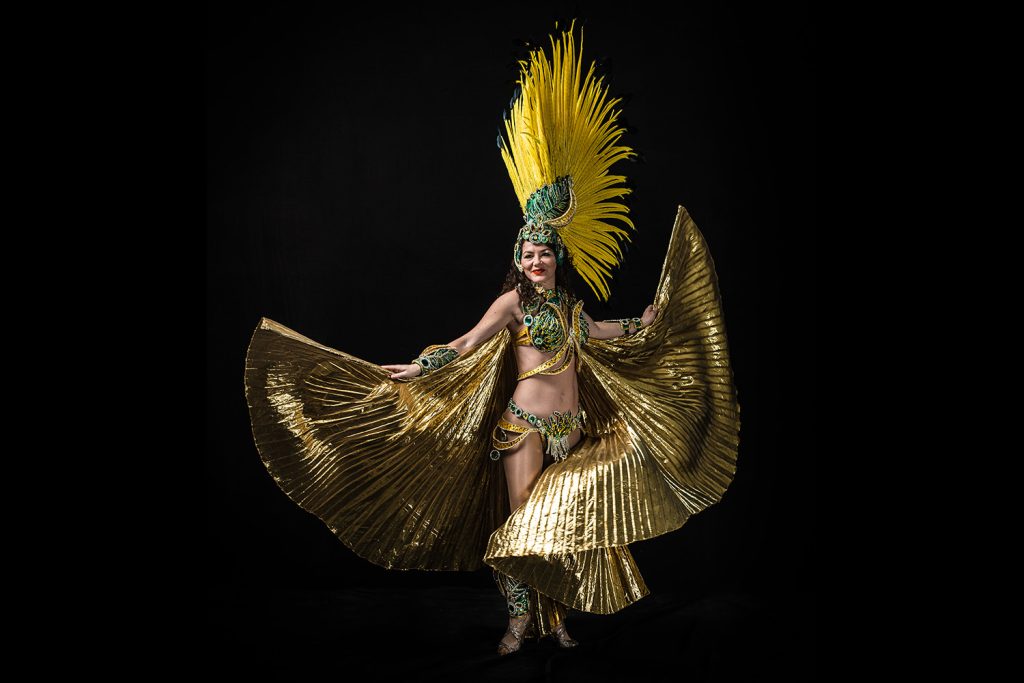 Samba-Tänzerin in einem leuchtenden Samba-Outfit in den Farben Gold, Grün und Gelb.